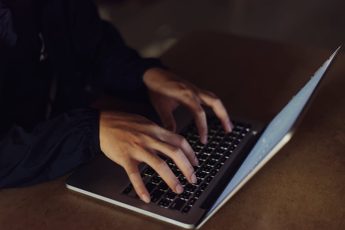 Professional developer working on dark mode MacBook in focused environment